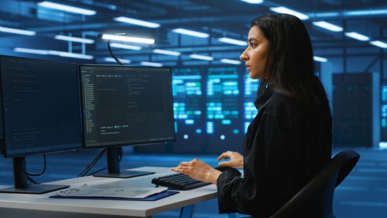 ABM College Cybersecurity graduate sitting at a desk with a computer