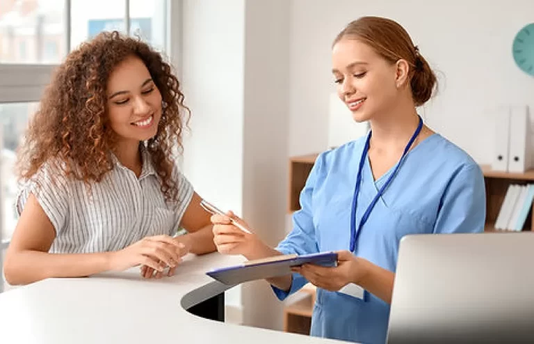 medical office assistant diploma graduate holding a pen and looking at the patient