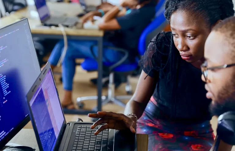 a Web Design and Development Diploma graduate explaining coding on a laptop to a person