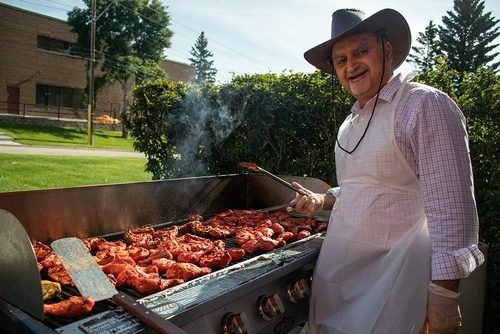 a man wearing a cowboy hat grilling meat outdoors